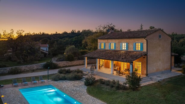 A two-story house with a swimming pool and outdoor seating area.