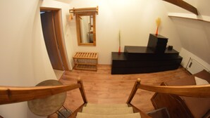 Een trap met houten leuningen die leidt naar een kamer met een bankje, een spiegel en een klein altaar met kaarsen.