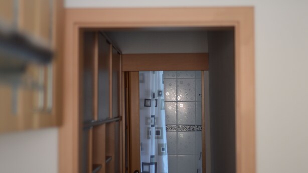 Een deuropening die leidt naar een kamer met een gordijn met een patroon en een betegelde muur.