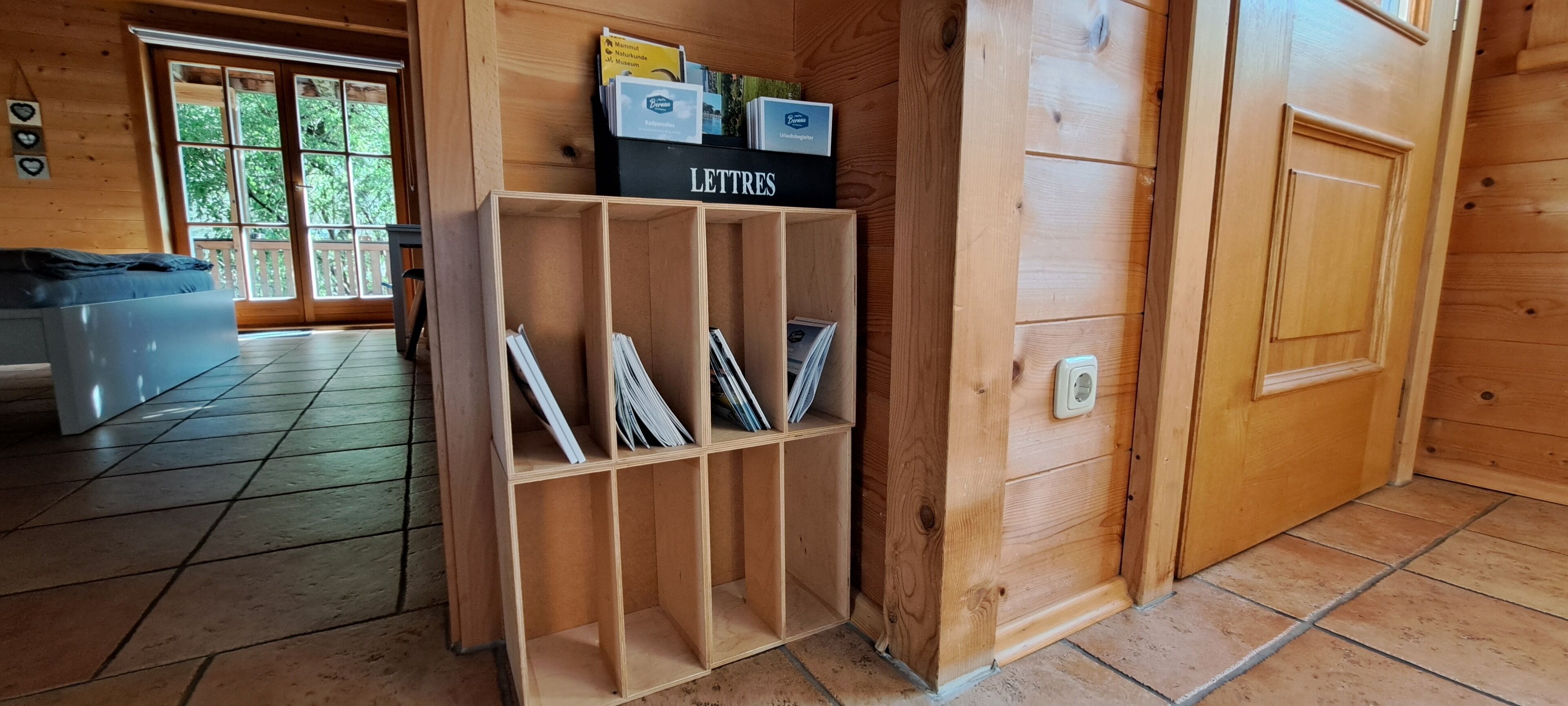 Un intérieur en bois avec une bibliothèque sur laquelle est inscrit le mot « LETTRES » et une porte donnant sur une autre pièce.