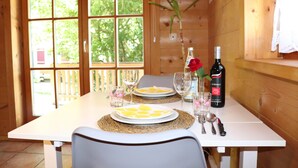 Un intérieur en bois avec une table mise pour un repas, comprenant des assiettes, des verres et une bouteille de vin.