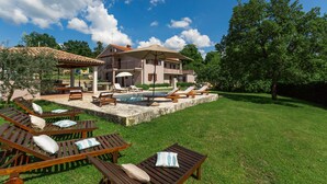 Ein geräumiges Haus mit Swimmingpool, Liegestühlen im Freien und einem gepflegten Rasen.