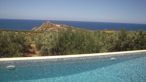 Una piscina con vistas despejadas al mar y una colina rocosa al fondo.