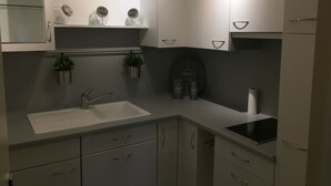 A modern kitchen with a white countertop, stainless steel sink, and cabinets. There are potted plants on the countertop and a BISTROT CAFE sign on the wall. - Apartment in a Richmond hill residence (Tours)