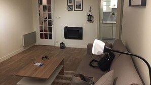 A living room with a sofa, a coffee table, a fireplace, and a door leading to a kitchen. - Apartment in a Richmond hill residence (Tours)