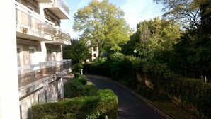 A narrow road flanked by lush greenery and a multi-story building with balconies. - Apartment in a Richmond hill residence (Tours)