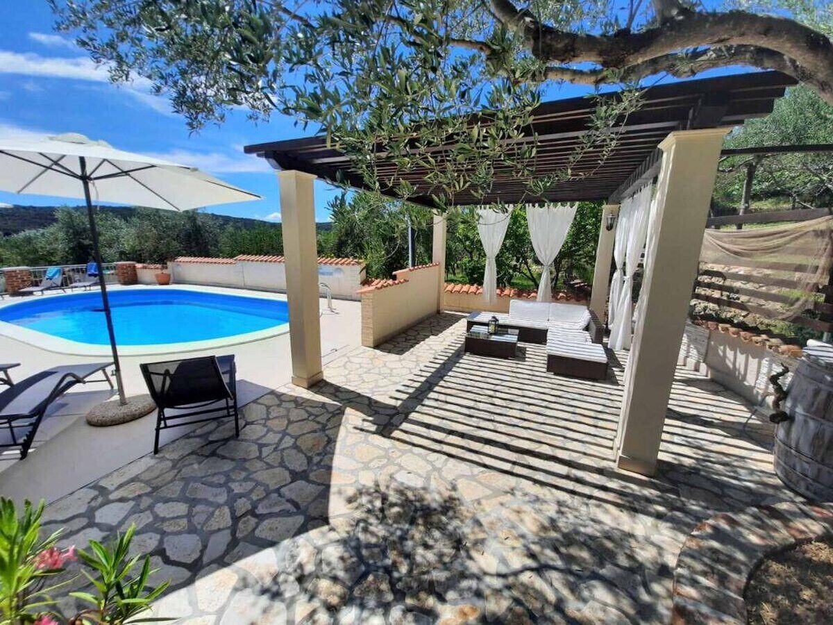 Un espace aménagé au bord de la piscine, avec une pergola, des chaises longues et une terrasse en pierre.