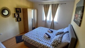 Ein Schlafzimmer mit Bett, Kleiderschrank, Spiegel und einem fenster mit Vorhängen.