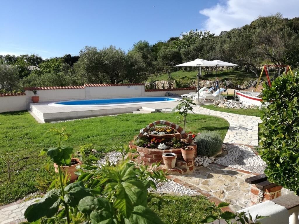 Un jardin avec une piscine, un foyer en briques et un espace aménagé avec des plantes en pot.
