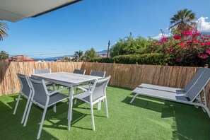 An outdoor patio with a table and chairs, surrounded by a wooden fence and lush greenery. - Top modern penthouse, heated pool, garden, beach within walking distance, parking space (Puerto de la Cruz)