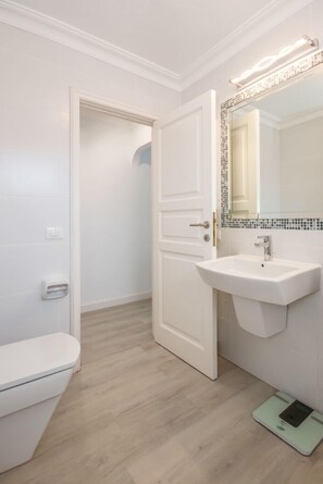A bathroom with a white toilet, a sink with a mirror, and a weighing scale on the floor. - Top modern penthouse, heated pool, garden, beach within walking distance, parking space (Puerto de la Cruz)