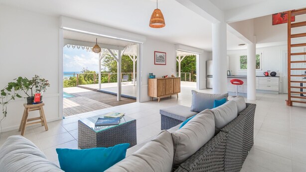 A spacious living area with a large sofa, a coffee table, and a view of the ocean.