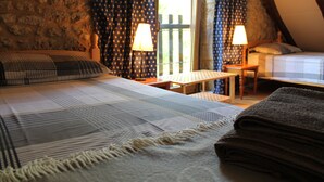 A cozy bedroom with two beds, a wooden table, and a window with curtains. - Charming Individual cottage" La Petite Grange" for maximum 4 people   (Puybrun)