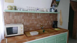 A kitchen with a microwave, sink, and various jars on the counter.