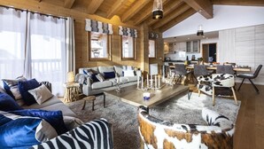Ein geräumiges Wohnzimmer mit Holzboden, einer Sofagarnitur, einem Couchtisch und einem Essbereich mit Stühlen und Tisch.
