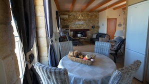 A cozy living room with a stone wall, wooden beams, wicker furniture, and a central table with a basket of snacks. - Sea-view villa, 1.5 km from beaches, private heated pool (optional). (KONTOMARI)