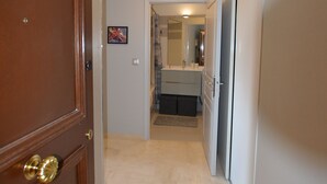 A hallway with a wooden door, a bathroom with a mirror, and a tiled floor. - AMAZING APARTMENT LOFT NEAR THE BEACHES (Cap-D'ail)