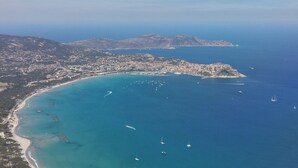 An aerial view of a coastal town with a beach, boats, and a mountainous backdrop. - Stunning 82m² air-conditioned 4-bedroom apartment in a villa in Calvi (Calvi)