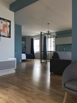 Ein modernes Wohnzimmer mit Bett, einer Couch und einer Küchenzeile.