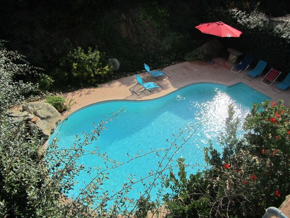 A swimming pool with lounge chairs and an umbrella, surrounded by rocks and greenery. - Haven of peace Cosy air-conditioned studio 16 m2+ Swimming pool for 2 persons (Porto-Vecchio)