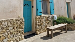A building with a stone foundation, a blue door, and a window with blue shutters. - Haven of peace Cosy air-conditioned studio 16 m2+ Swimming pool for 2 persons (Porto-Vecchio)