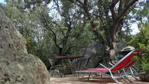 Outdoor seating with a table and chairs, a red lounge chair, and a staircase leading up to a higher area. - Haven of peace Cosy air-conditioned studio 16 m2+ Swimming pool for 2 persons (Porto-Vecchio)