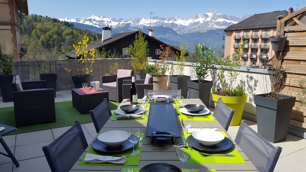 An outdoor dining area with a view of snow-capped mountains, furnished with wicker chairs and tables, and surrounded by potted plants. - In HEART of St Gervais, PARKING, WIFI ... (Saint-Gervais-Les-Bains)