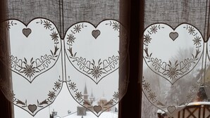 A window with heart-shaped designs and a view of a snowy landscape with a small Christmas tree. - In HEART of St Gervais, PARKING, WIFI ... (Saint-Gervais-Les-Bains)