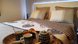 A neatly made bed with patterned bedding, a tray with croissants, coffee mugs, and a teapot. - In HEART of St Gervais, PARKING, WIFI ... (Saint-Gervais-Les-Bains)