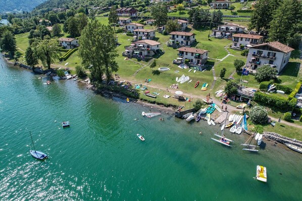A lakeside property with multiple buildings, boats, and a well-maintained lawn. - Directly on the lake with terrace for seven people (Tre Capitelli)