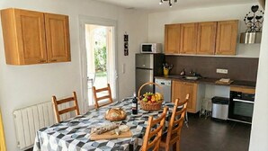Une cuisine de taille réduite, dotée de meubles en bois, d’un four à micro-ondes et d’un réfrigérateur.