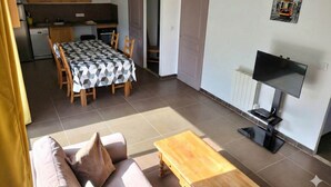 Un espace de vie compact comprenant un coin repas, une kitchenette et un téléviseur.