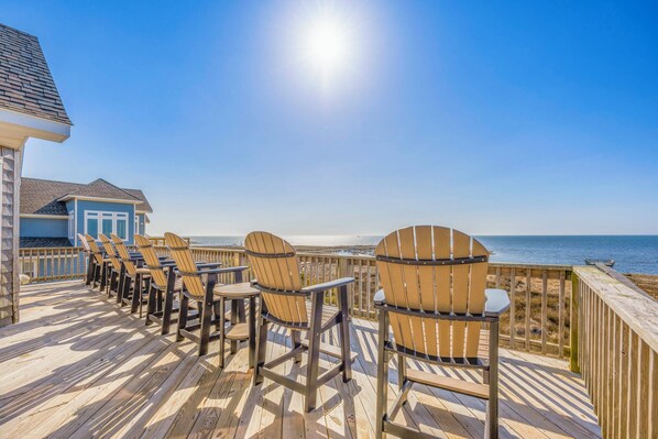A wooden deck with chairs and a view of the ocean.