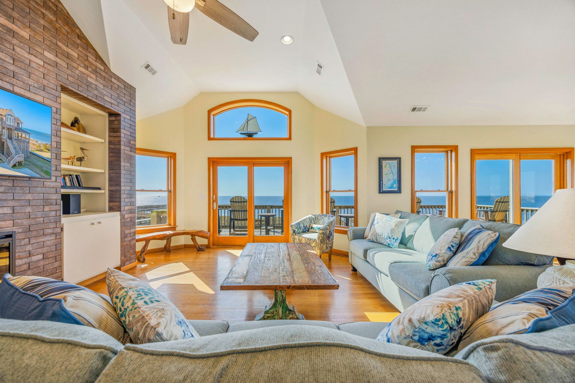 A spacious living room with a fireplace, a large window overlooking the ocean, and a cozy seating area.