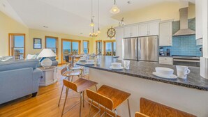 A spacious kitchen with a large island, stainless steel appliances, and a view of the ocean. - Sweet Tranquility – Soundfront Retreat w/ Pool, Hot Tub, Game Room & Tiki Bar (Salvo)