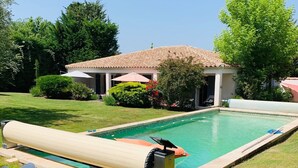 A swimming pool with a water slide, surrounded by a well-maintained lawn and a house with a tiled roof. - PRETTY FAMILY HOUSE IN PROVENCE (Éguilles)