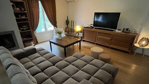 A living room with a large grey sofa, a wooden coffee table, a TV on a wooden cabinet, and a lamp on a side table. - PRETTY FAMILY HOUSE IN PROVENCE (Éguilles)