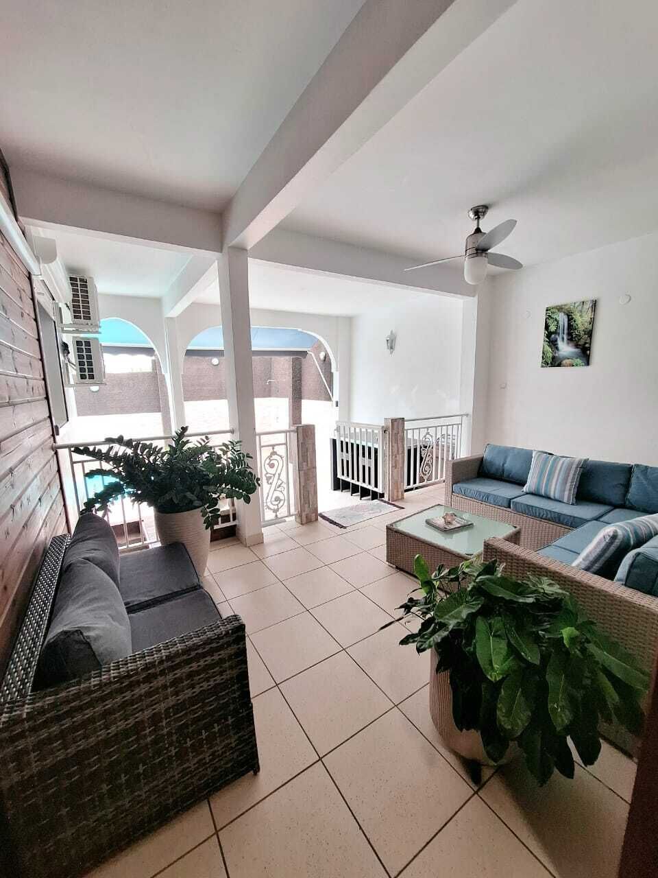 A spacious balcony with a wicker sofa, a blue sofa, and potted plants.
