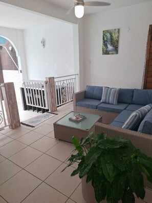 Una sala de estar con un sofá, una mesa de centro y una planta grande en maceta.