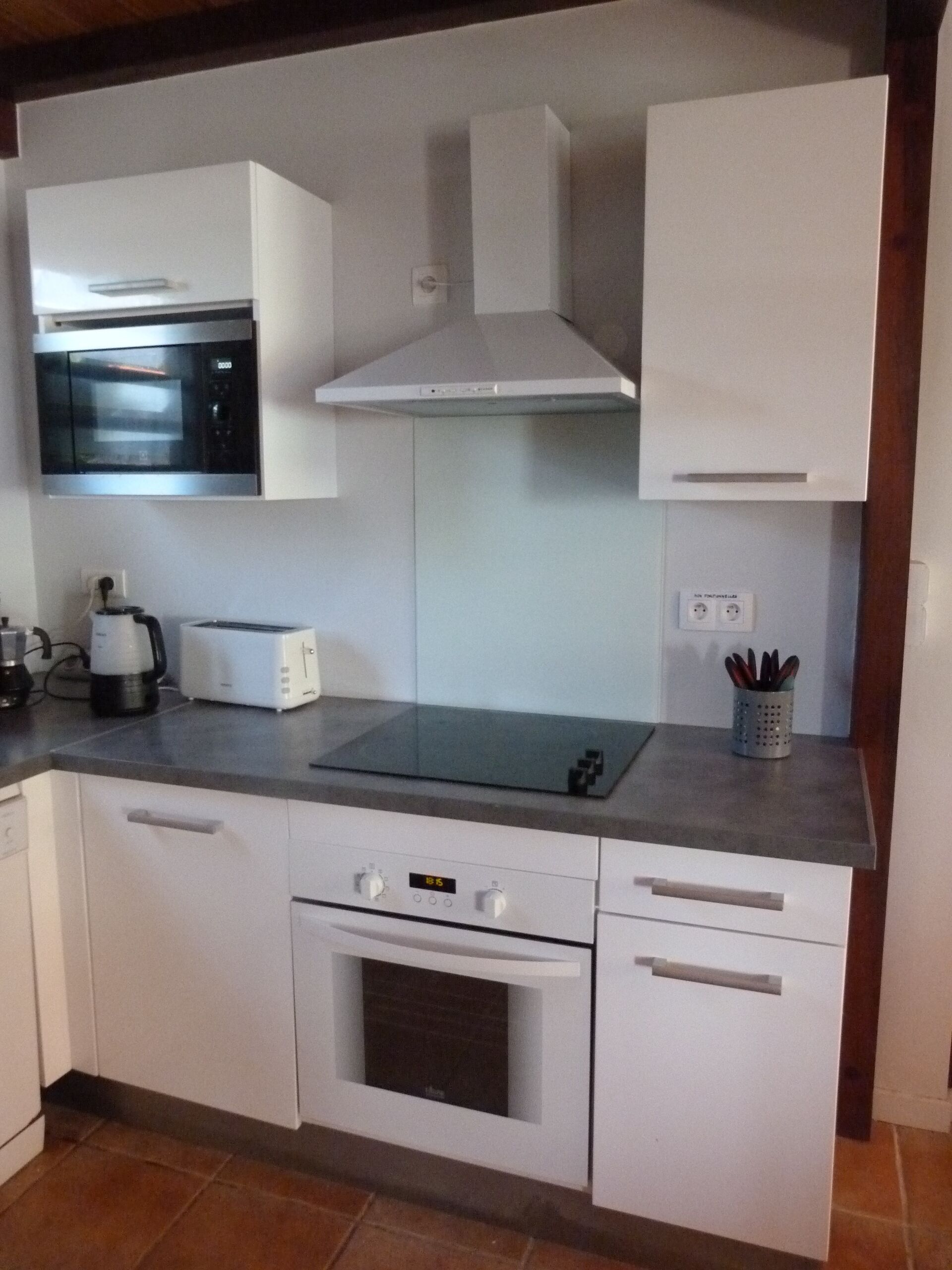 A kitchen with white cabinets, a microwave, a toaster, and an oven.