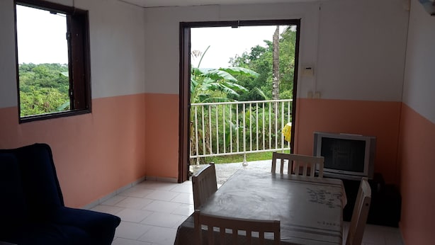Ein Zimmer mit Balkon, Fernseher, Tisch und Stuhl.