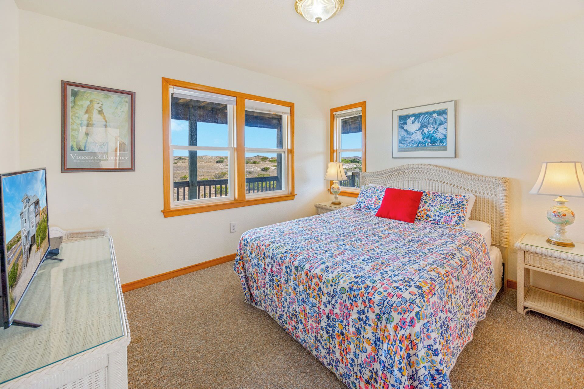 A bedroom with a large bed, a nightstand, a lamp, and a window with a view of the landscape.