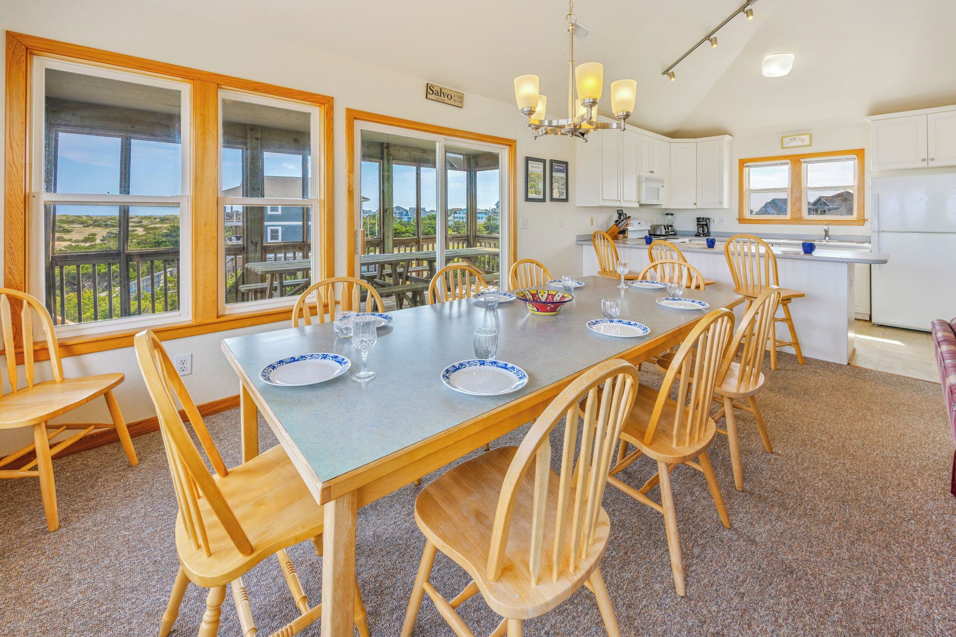 Un comedor con una mesa dispuesta para seis, sillas de madera y ventanas amplias con vistas al exterior.