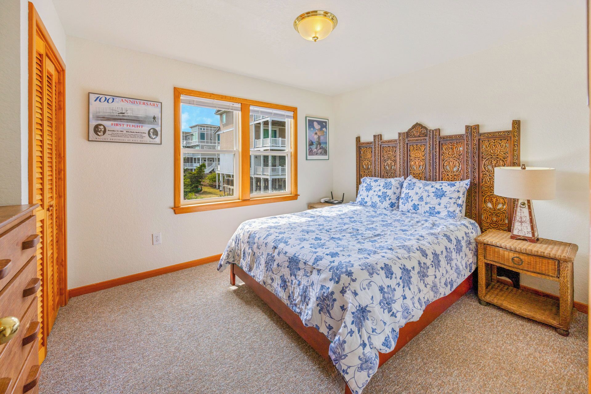 Quarto com cama, mesa de cabeceira, luminária, janela com vista e um certificado emoldurado na parede.