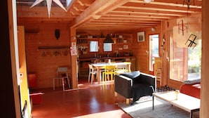 A wooden cabin interior with a dining area, kitchen, and seating space. - THE family chalet, ideal winter and summer! View at the top! (Morillon)