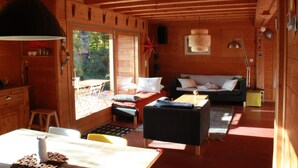 A wooden cabin interior with a dining area, a sofa, and a large window. - THE family chalet, ideal winter and summer! View at the top! (Morillon)
