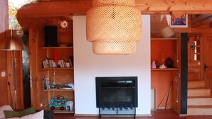 A cozy living room with a fireplace, wooden walls, a woven light fixture, and a bookshelf. - THE family chalet, ideal winter and summer! View at the top! (Morillon)