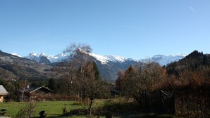 A rural landscape with a house, a fenced field, and snow-capped mountains in the background. - THE family chalet, ideal winter and summer! View at the top! (Morillon)