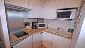 A compact kitchen with white cabinets, a microwave, a toaster, a coffee maker, and a dishwasher.