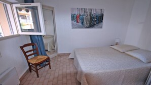 A bedroom with a bed, a chair, a window, and a door.